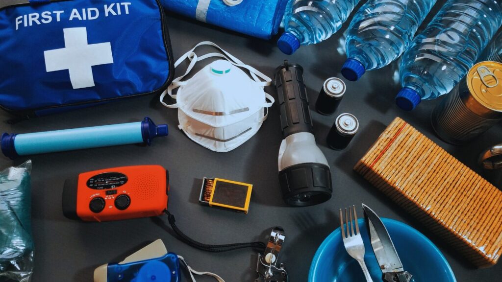 非常用持ち出し袋の中身を俯瞰で撮影。水、ラジオ、マスク、ライトなどが整然と並ぶ。