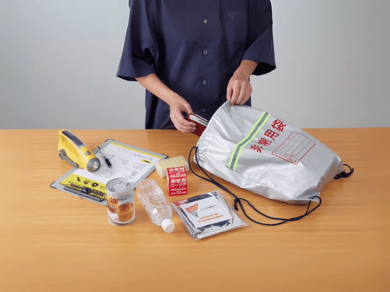 テーブルの上に防災グッズを並べて中身を確認する一人暮らしの準備シーン